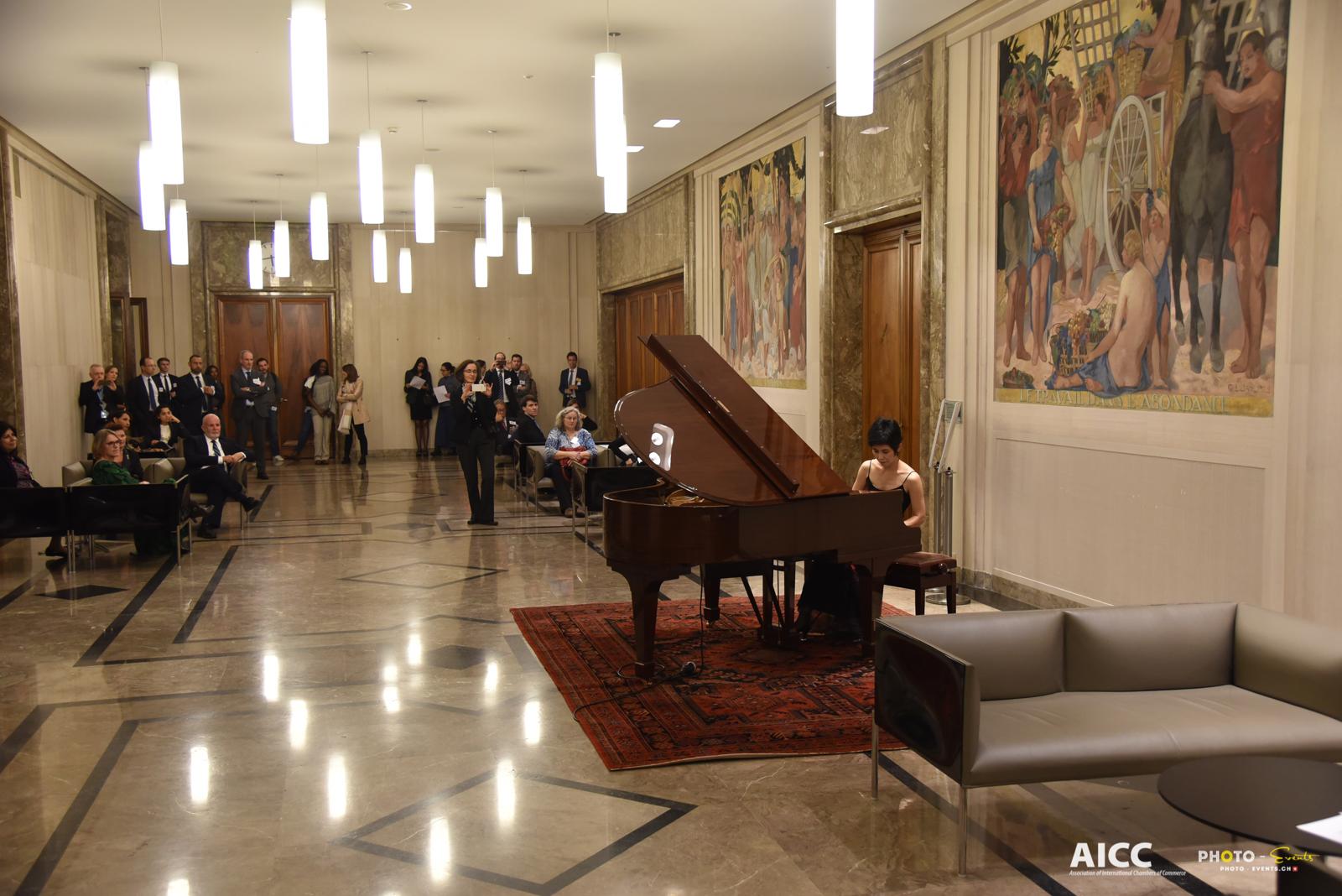 The audience standing and seated along the marble hall of the Centre William Rappard as Yuuko Suzuki plays