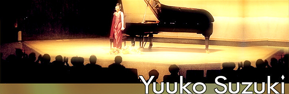 Yuuko Suzuki taking a bow after a recital, grand piano behind her on a lit stage